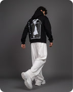 Person wearing a black hoodie with a graphic design on the back against a gray background