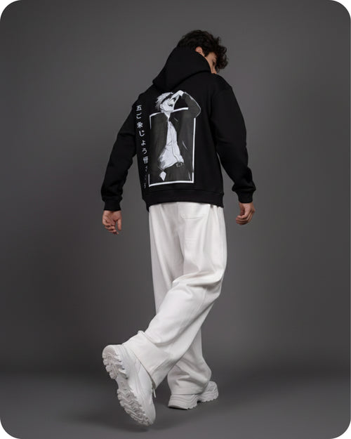 Person wearing a black hoodie with a graphic design on the back against a gray background