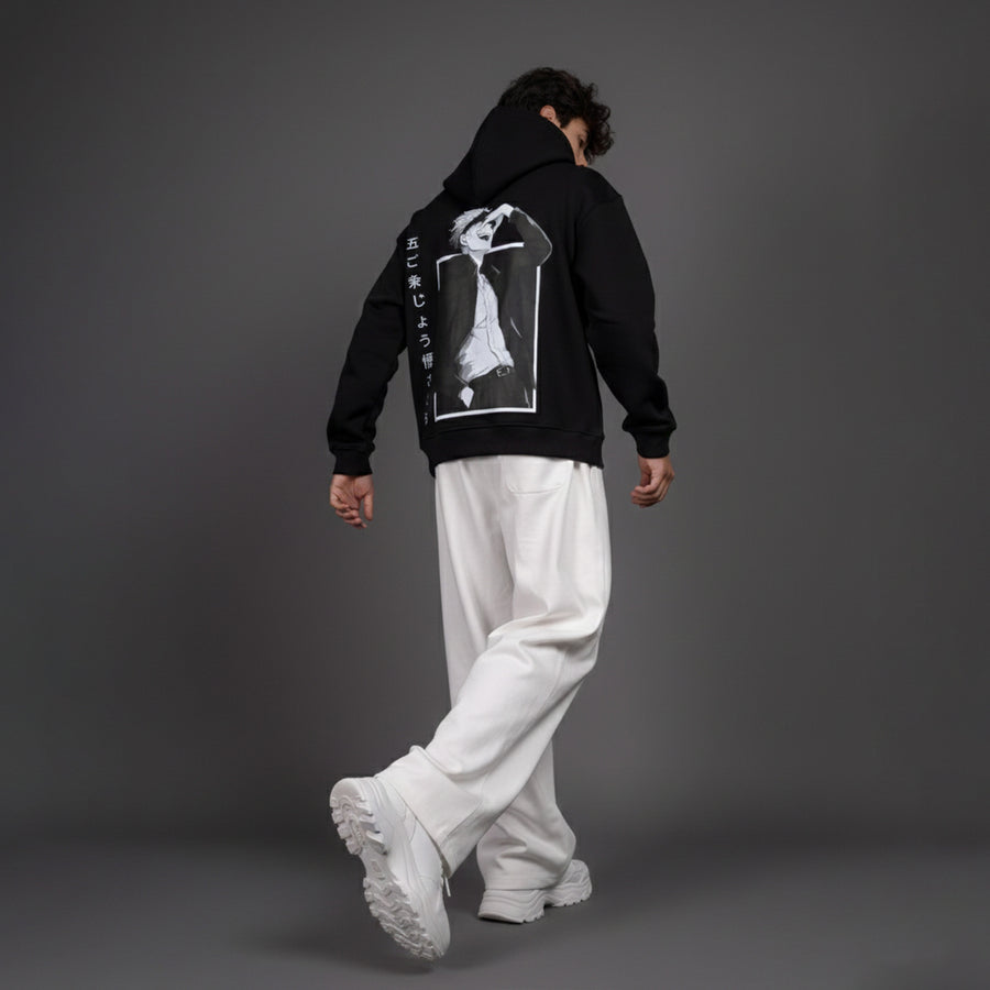 Person wearing a black hoodie with a graphic design on the back against a gray background