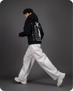 Person wearing a black jacket with a graphic design on a gray background