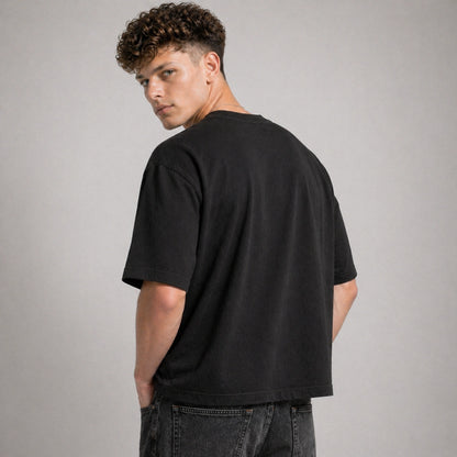 Man wearing a black t-shirt and jeans against a gray background