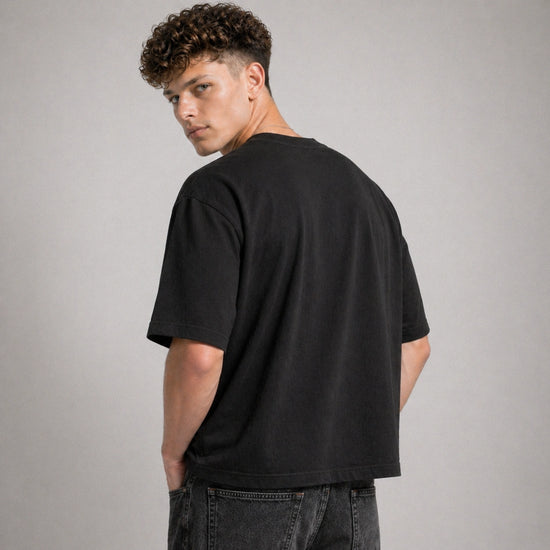 Man wearing a black t-shirt and jeans against a gray background