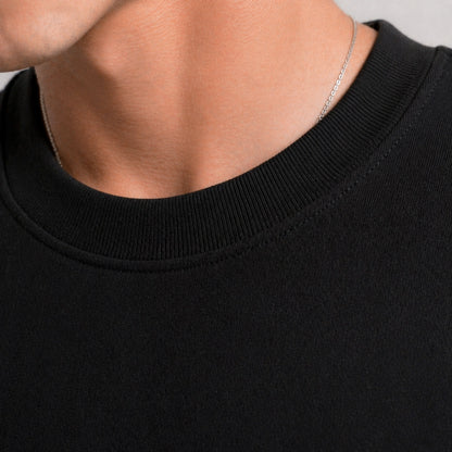 Close-up of a person wearing a black sweater with a silver necklace.