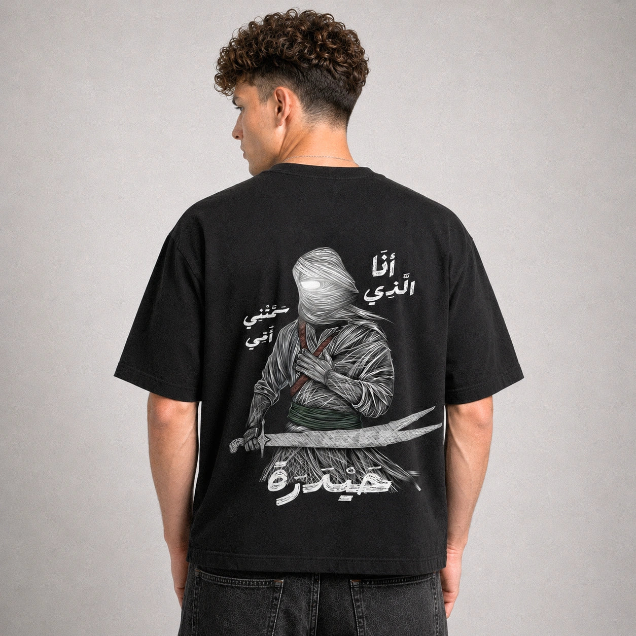 Person wearing a black t-shirt with a graphic design on the back against a gray background