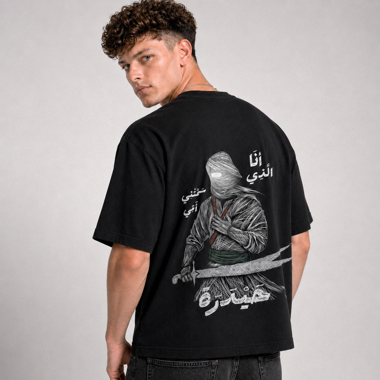 Person wearing a black t-shirt with a graphic design on the back against a gray background