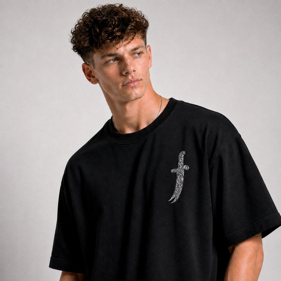 Man wearing a black t-shirt with a silver cross design on a gray background
