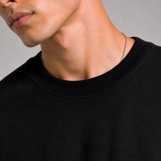 Close-up of a person wearing a black sweater against a gray background
