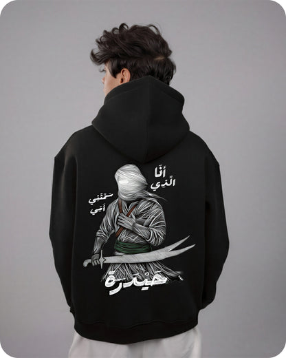 Person wearing a black hoodie with a graphic design on the back against a gray background