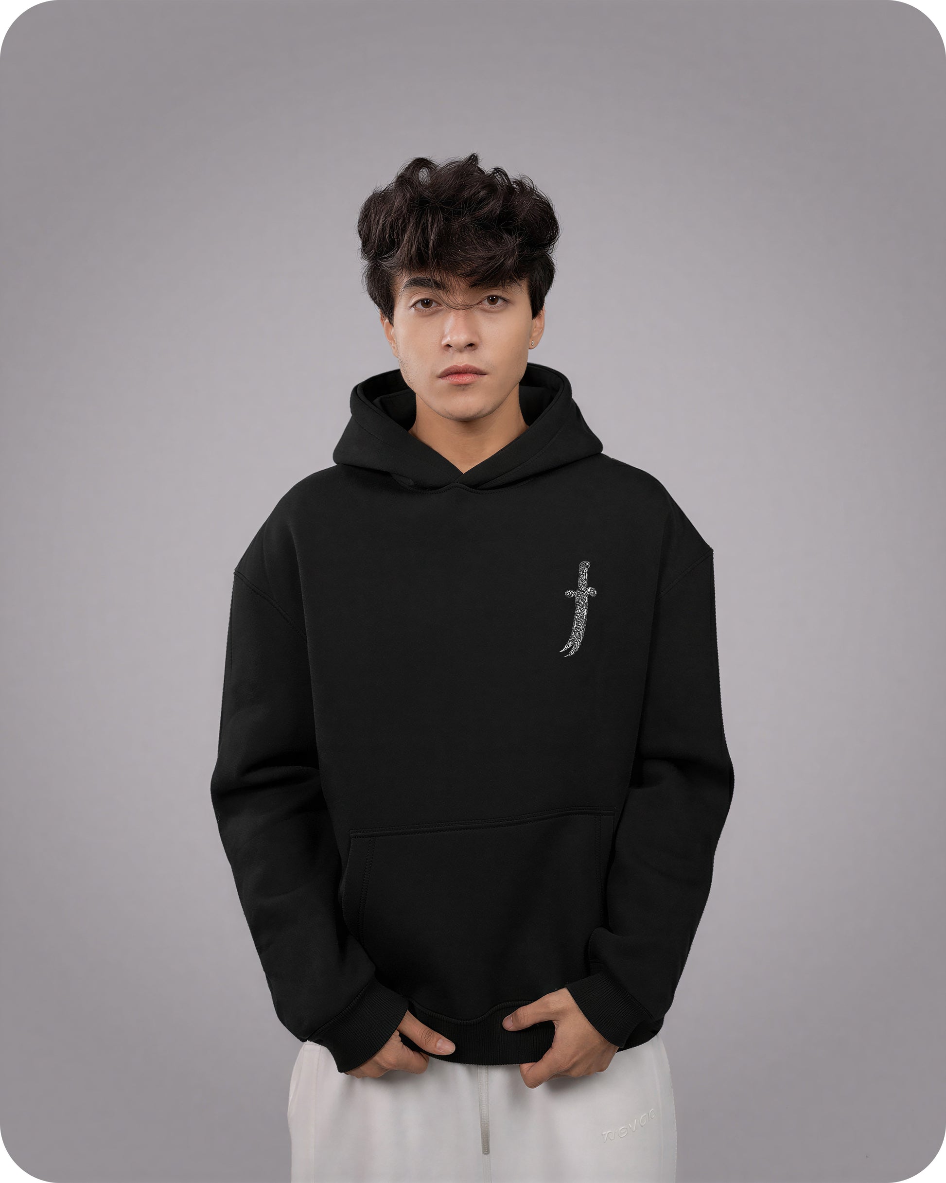 Person wearing a black hoodie with a small design on a gray background