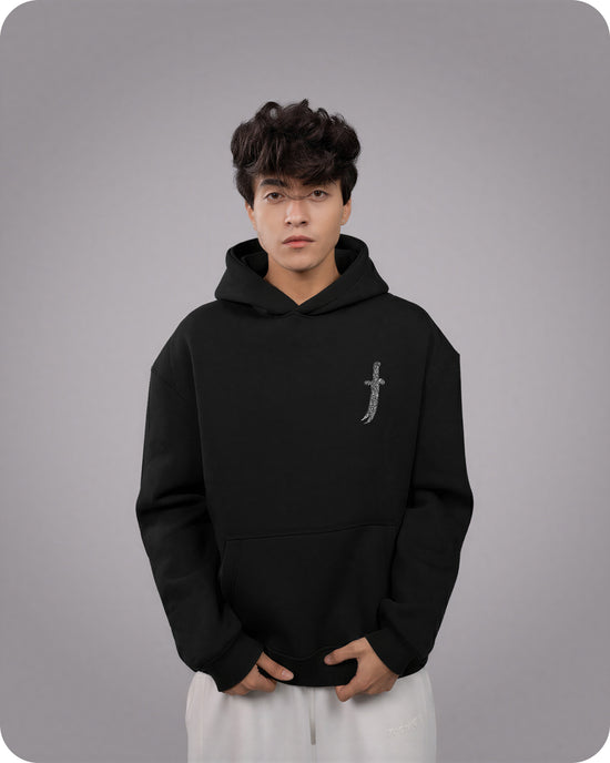 Person wearing a black hoodie with a small design on a gray background