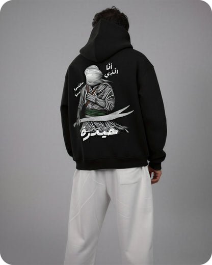 Person wearing a black hoodie with a graphic design on the back against a gray background