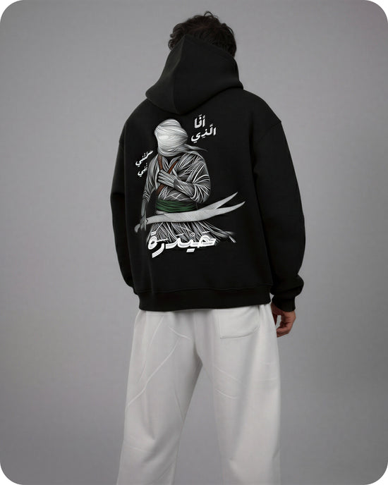 Person wearing a black hoodie with a graphic design on the back against a gray background