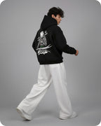 Person wearing a black hoodie with a graphic design on the back, standing against a gray background