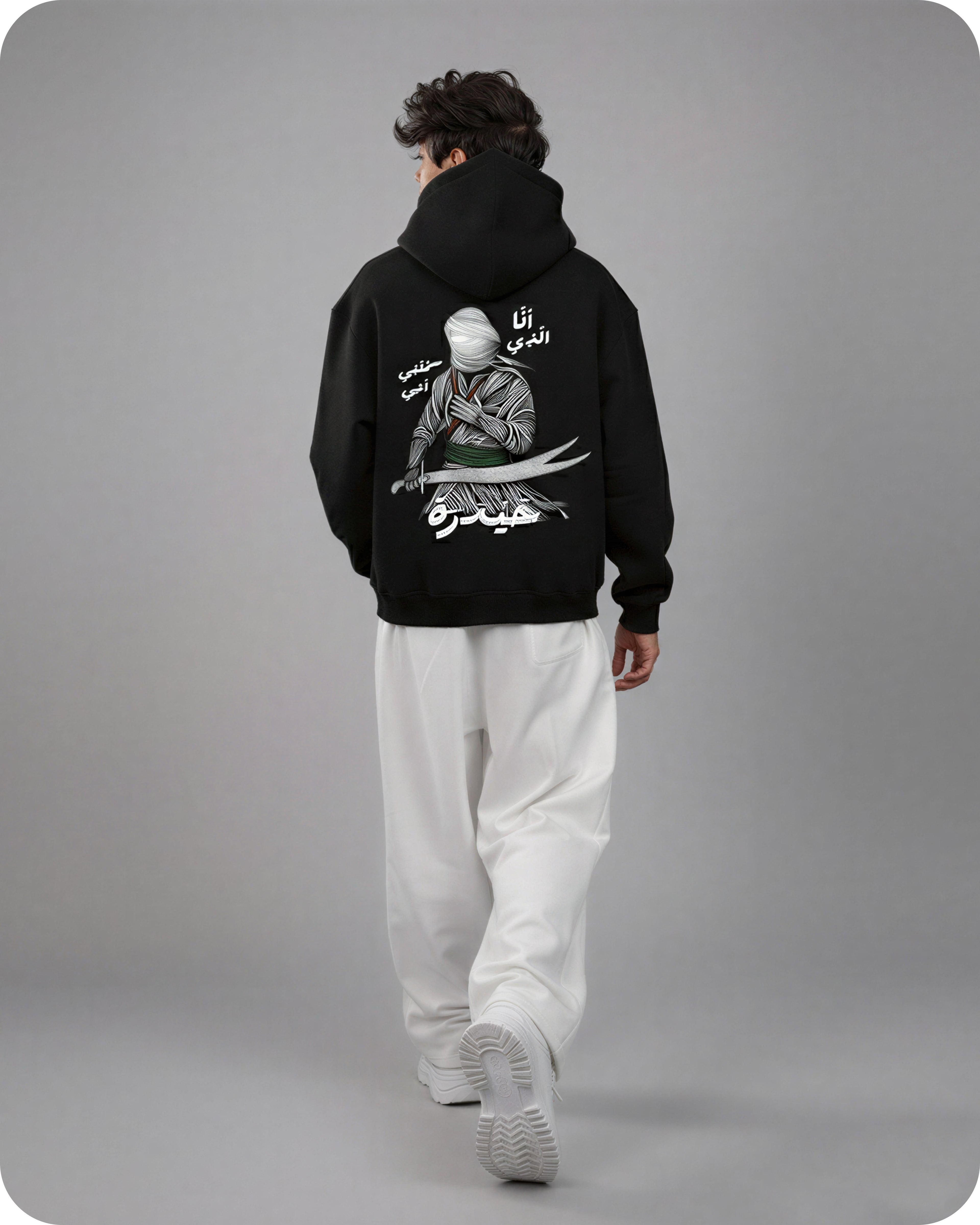 Person wearing a black hoodie with a graphic design on the back against a gray background