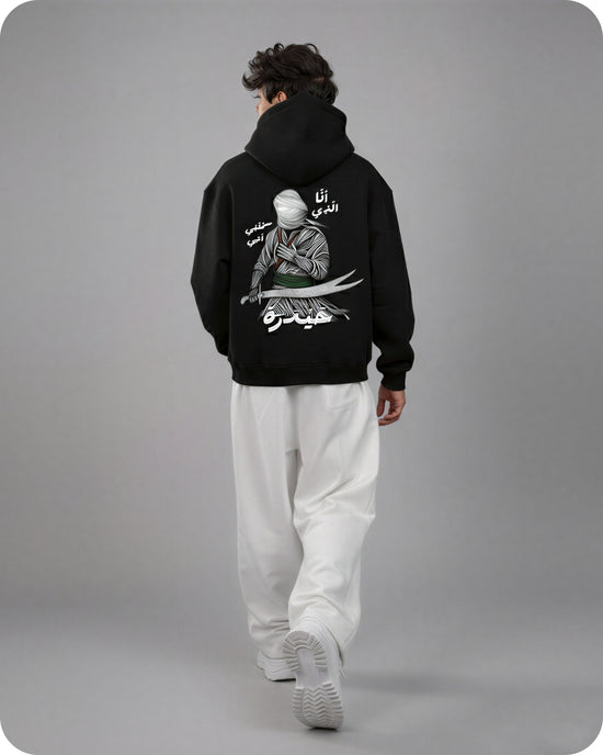 Person wearing a black hoodie with a graphic design on the back against a gray background