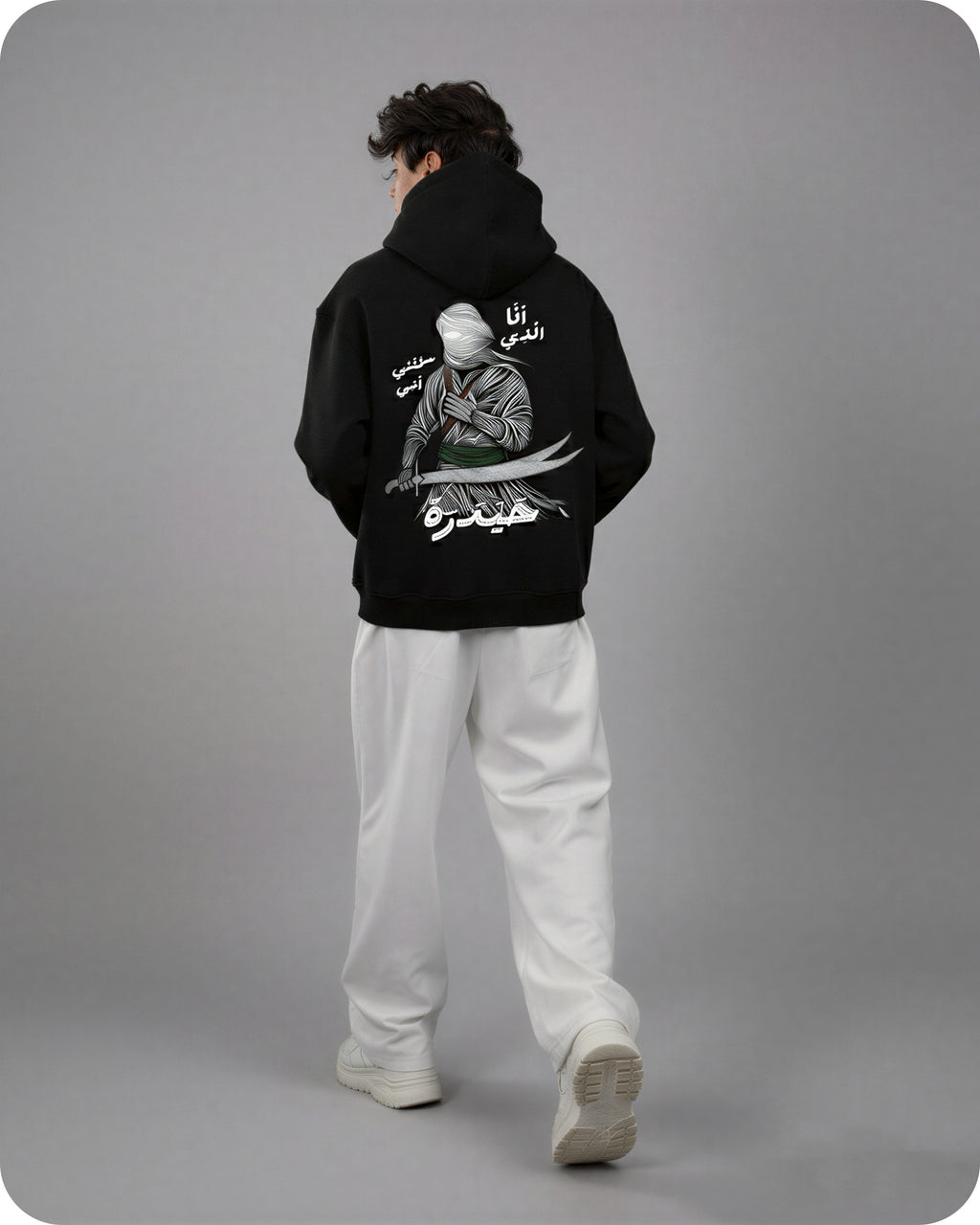 Person wearing a black hoodie with a graphic design on the back against a gray background