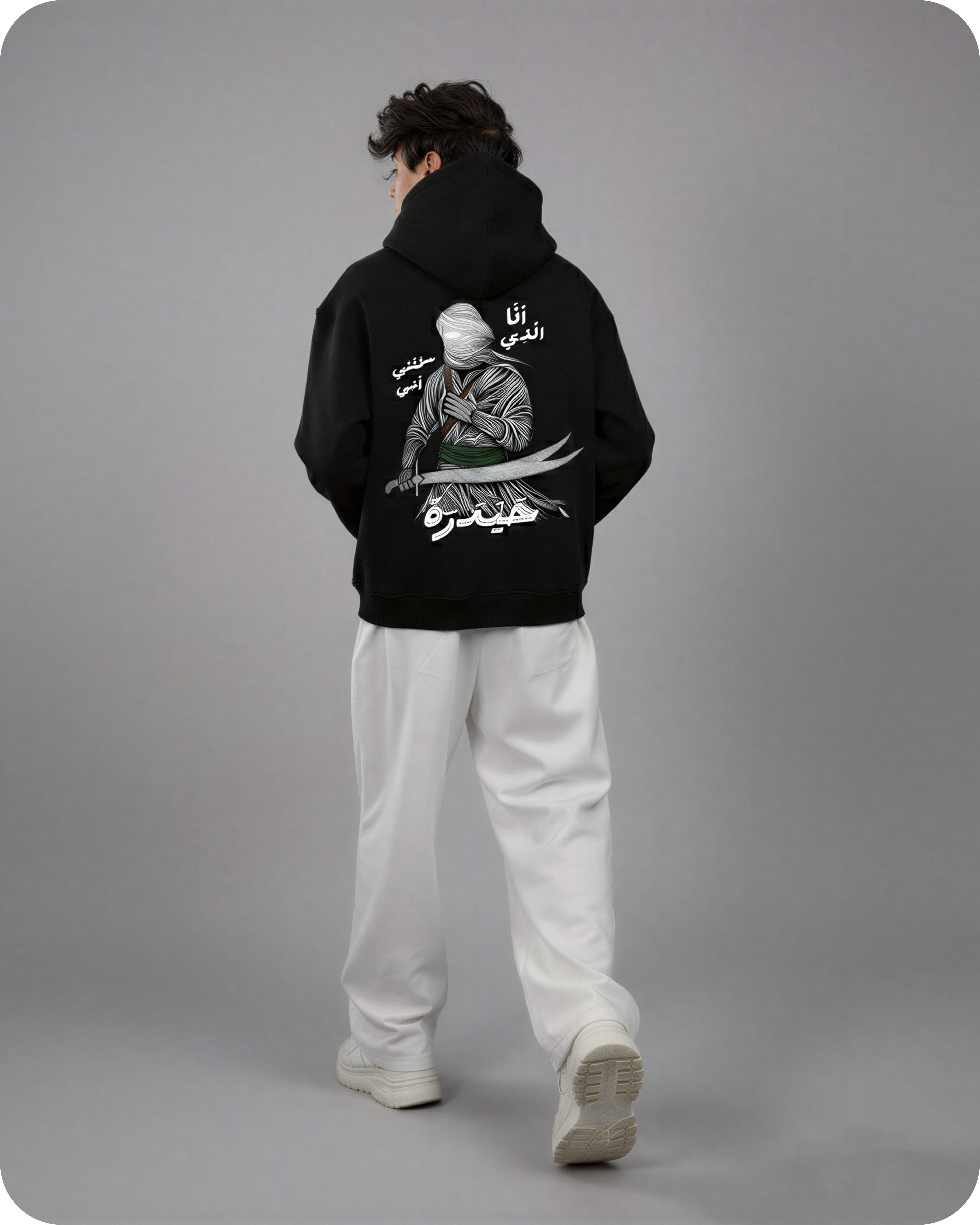 Person wearing a black hoodie with a graphic design on the back against a gray background