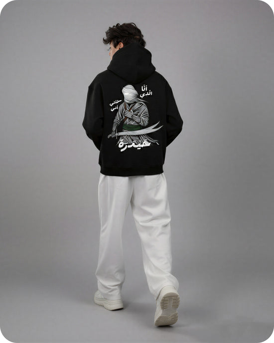 Person wearing a black hoodie with a graphic design on the back against a gray background