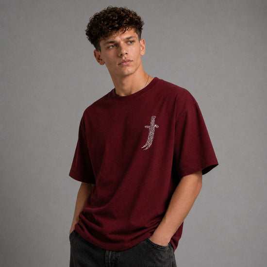 A man wearing a maroon short-sleeve t-shirt with a large graphic print on the back, shown from behind against a neutral gray background.