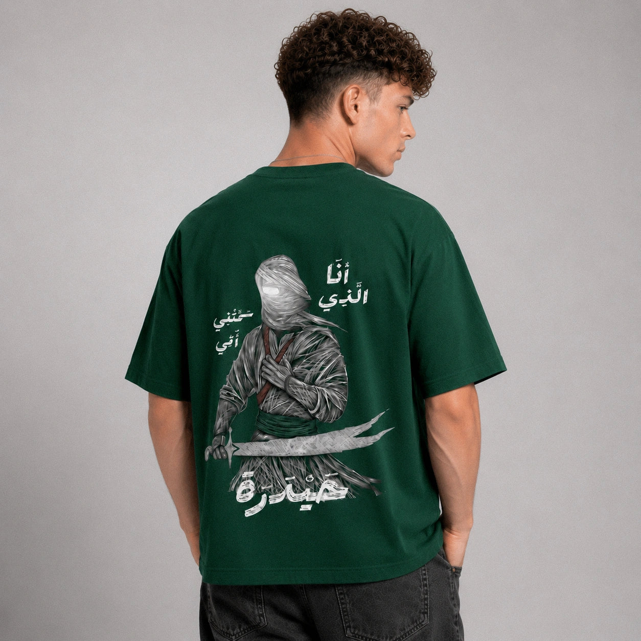 Person wearing a green t-shirt with a graphic design on the back against a gray background