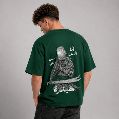 Person wearing a green t-shirt with a graphic design on the back, standing against a gray background