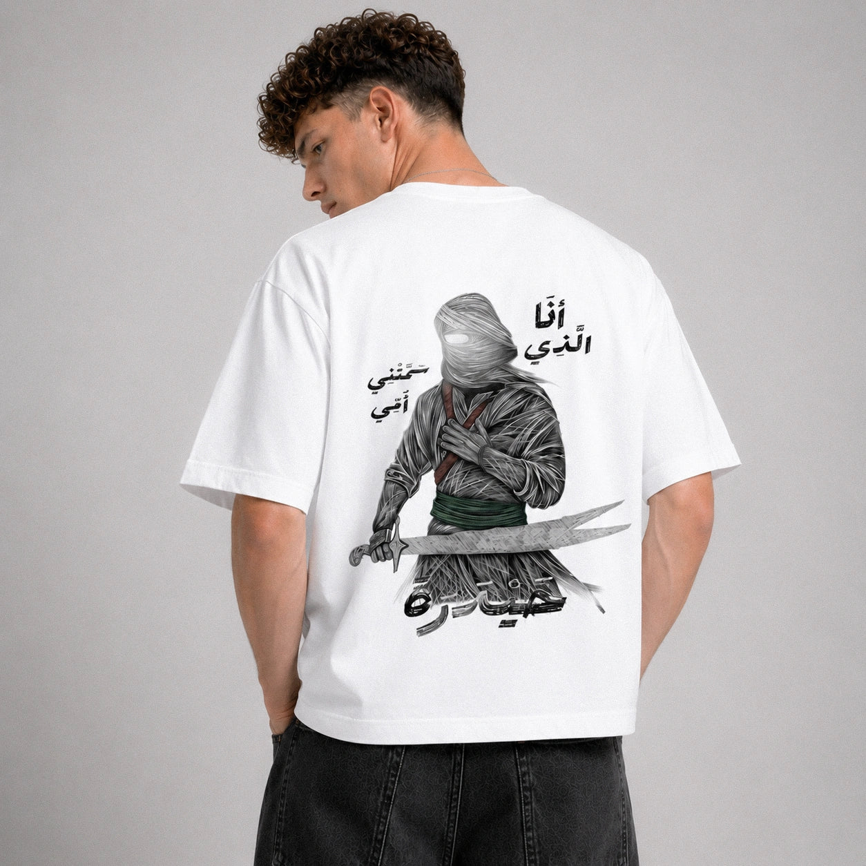 Person wearing a white t-shirt with a graphic design on the back against a gray background