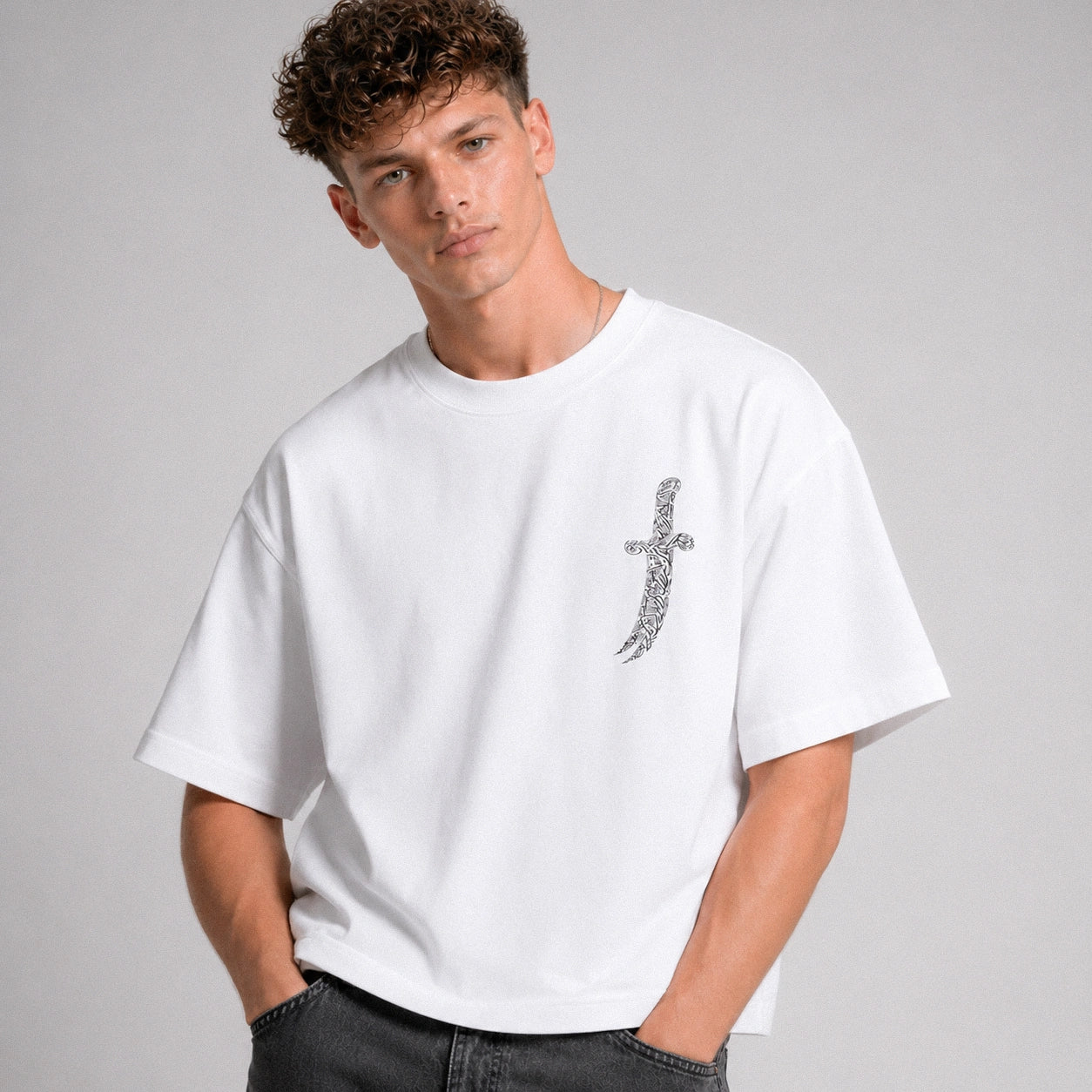Man wearing a white t-shirt with a decorative design on a gray background