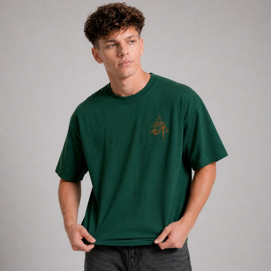 Man wearing a green t-shirt with a small logo on a gray background