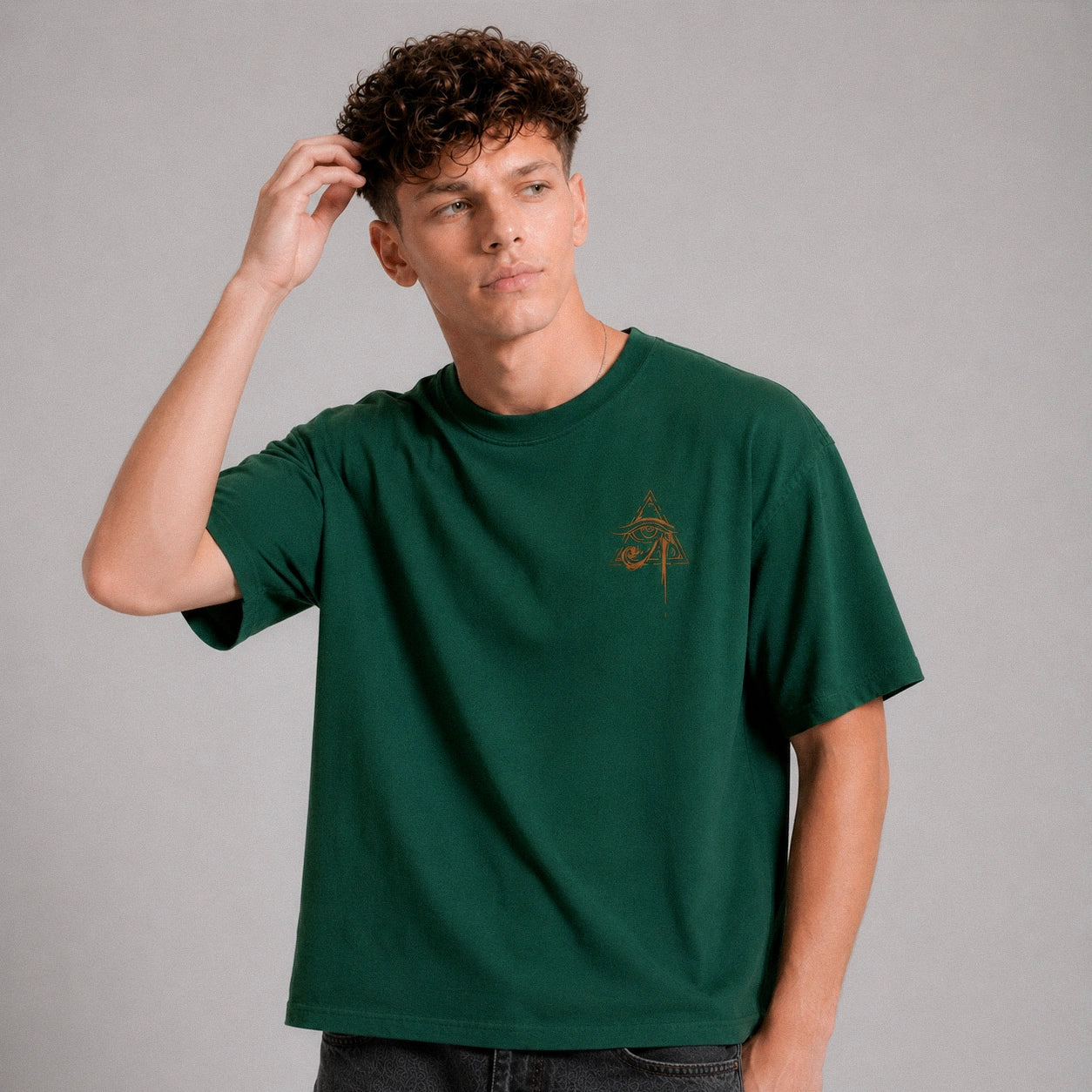 Man wearing a green t-shirt with a small logo on a gray background