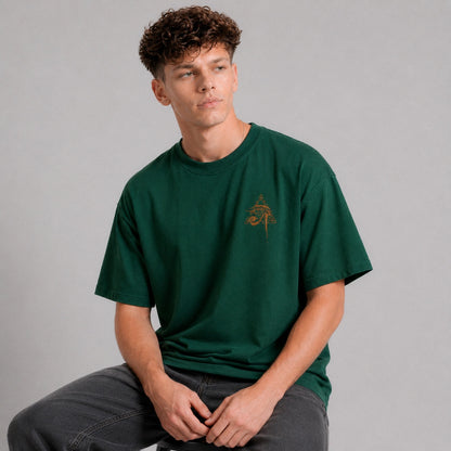 Man wearing a green t-shirt with a small logo on a gray background