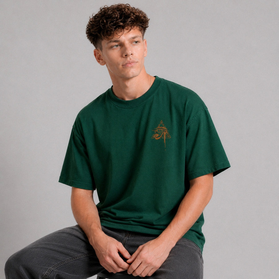 Man wearing a green t-shirt with a small logo on a gray background
