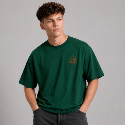Man wearing a green t-shirt with a small logo on a gray background