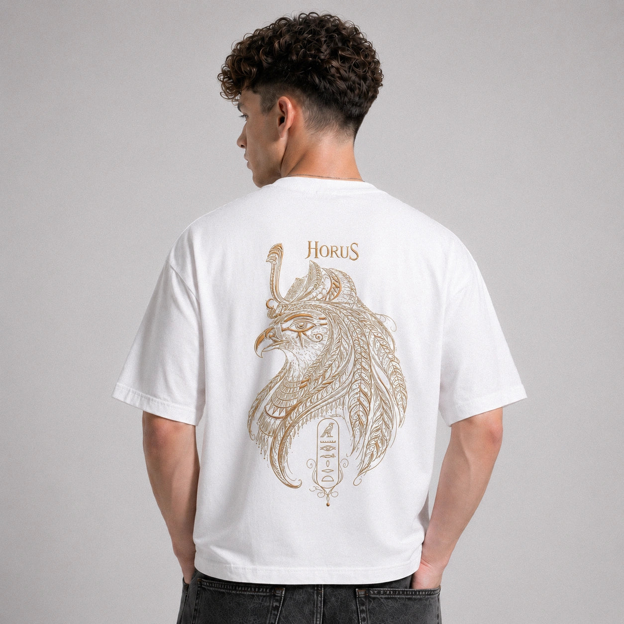 Person wearing a white t-shirt with a gold 'Horus' design on the back against a gray background