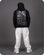 Person wearing a black hoodie with a graphic design on the back against a gray background