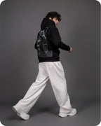 Person wearing a black hoodie, white pants, and white shoes on a gray background