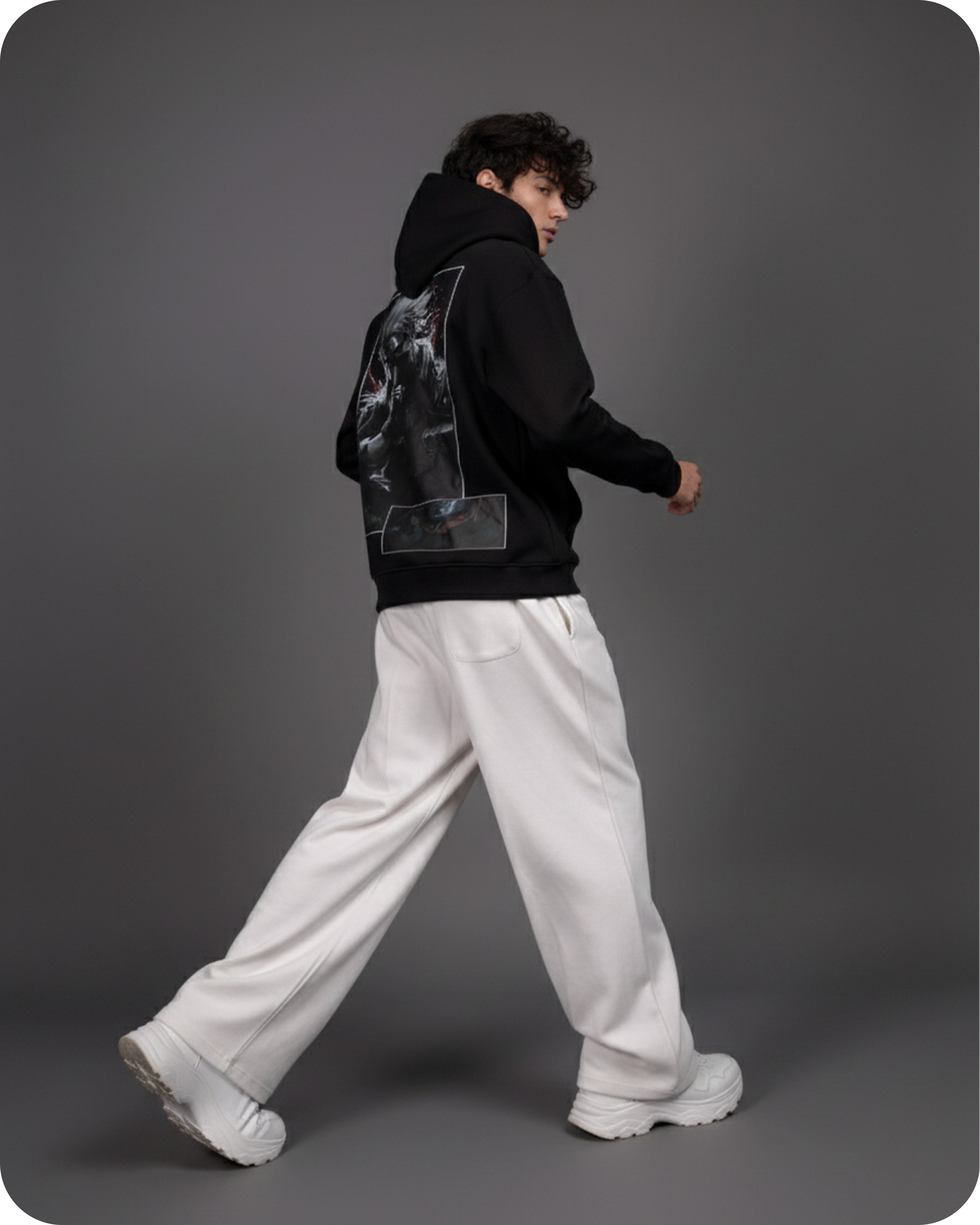 Person wearing a black hoodie, white pants, and white shoes on a gray background