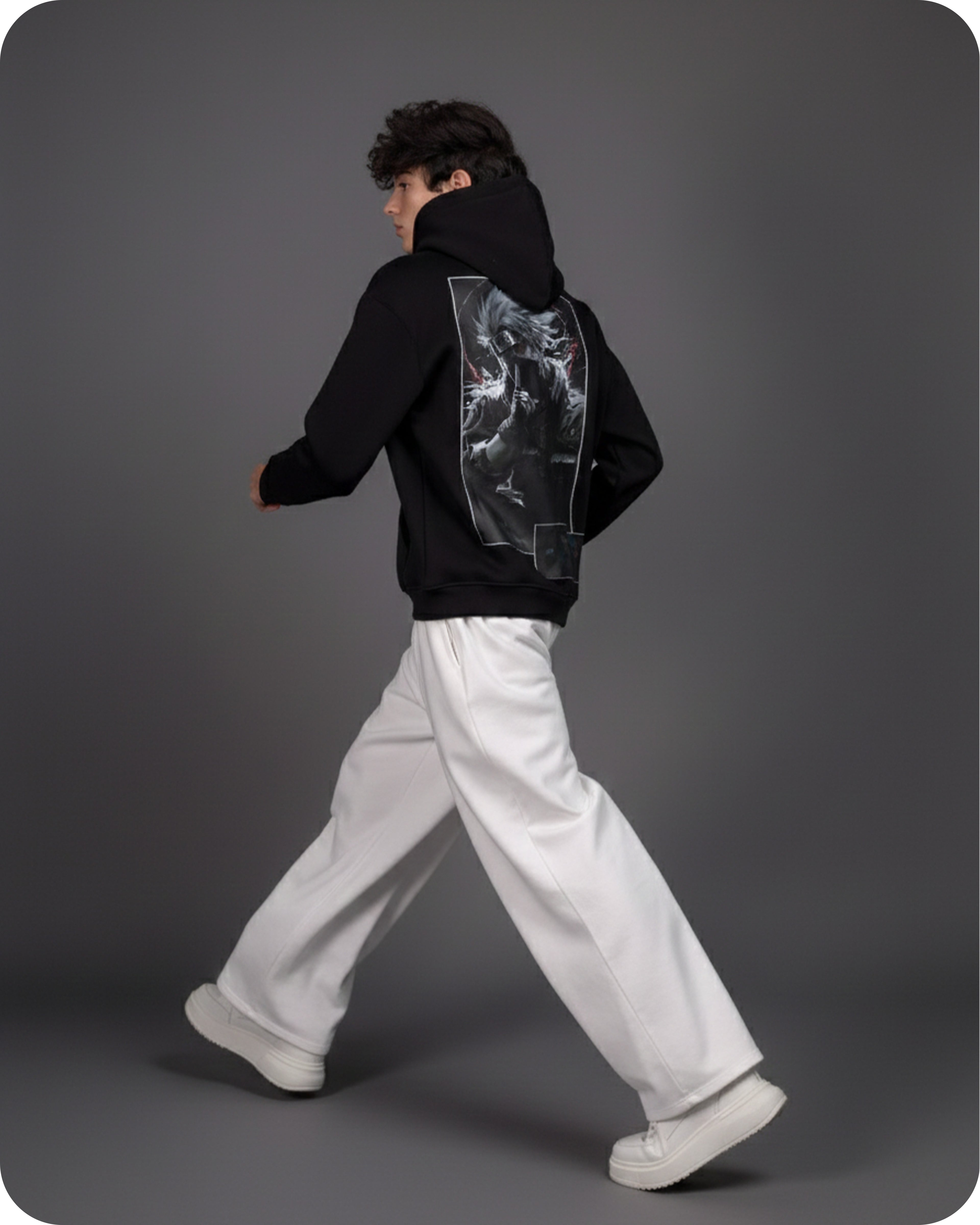 Person wearing a black hoodie with a graphic design on the back, walking against a gray background