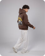 Person wearing a brown hoodie with a graphic design on a plain background