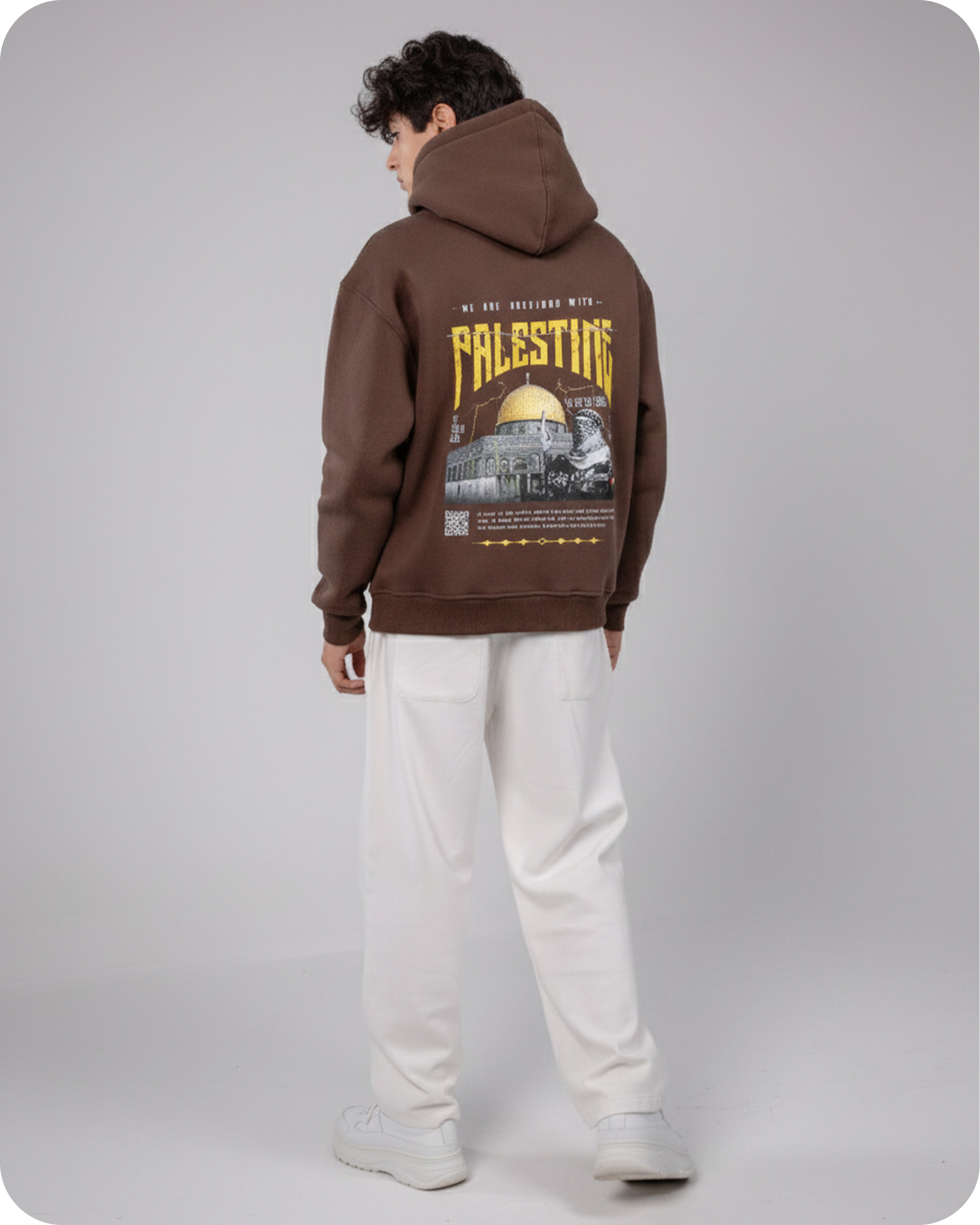 Person wearing a brown hoodie with 'Palestine' printed on the back, standing against a plain background.