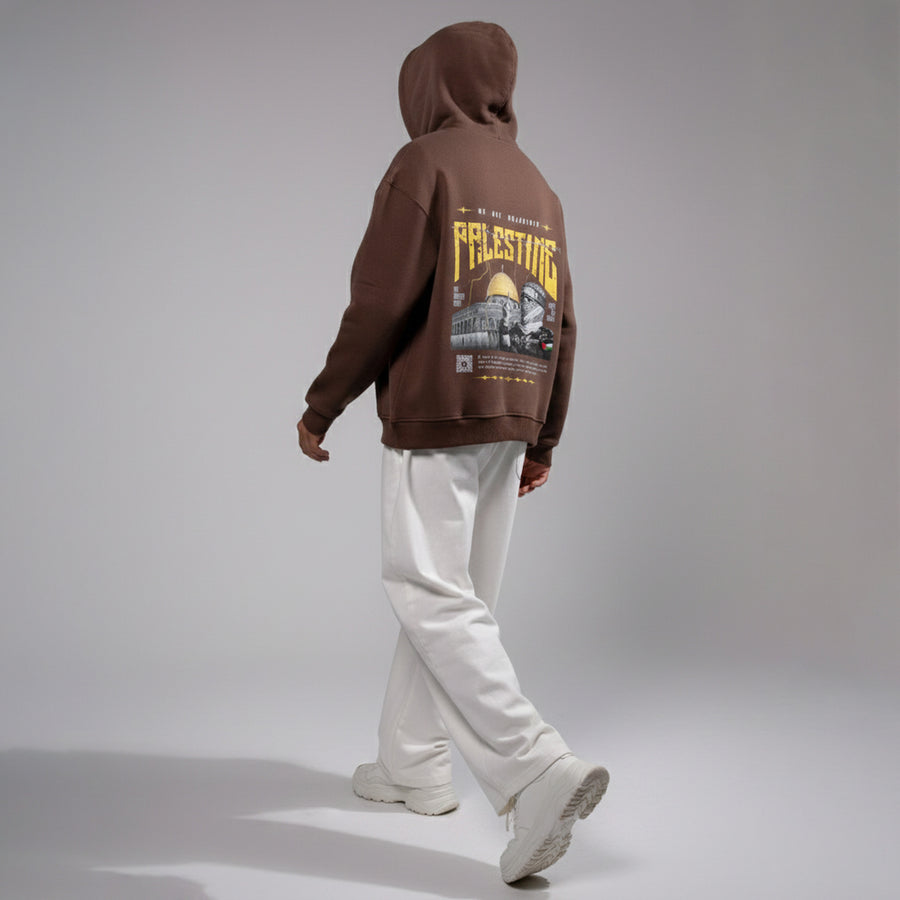 Person wearing a brown hoodie with graphic design on the back against a gray background
