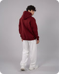 Person wearing a red hoodie and white pants on a gray background