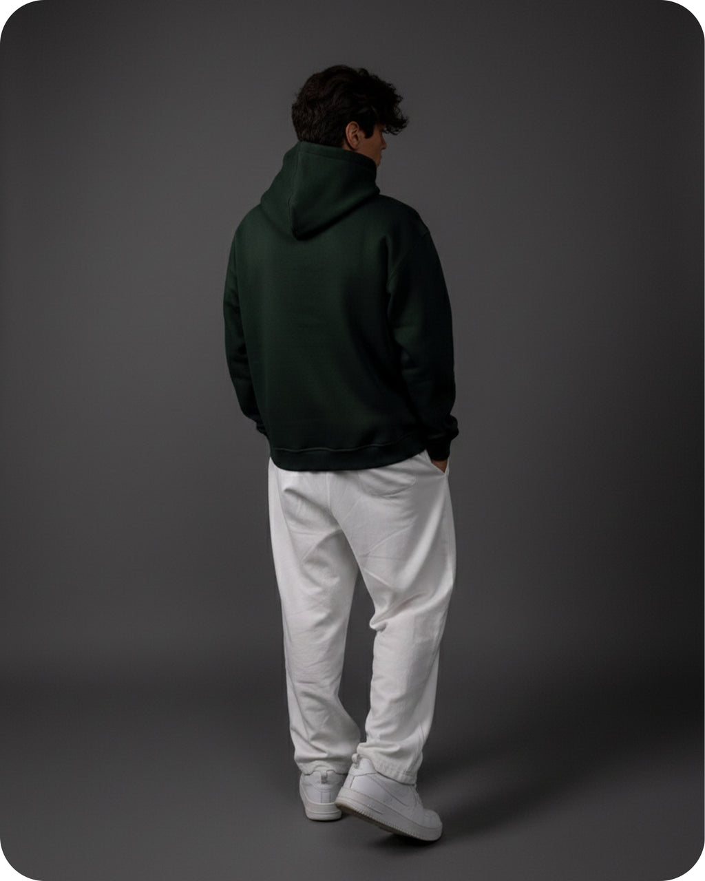 Person wearing a dark green hoodie and white pants on a gray background