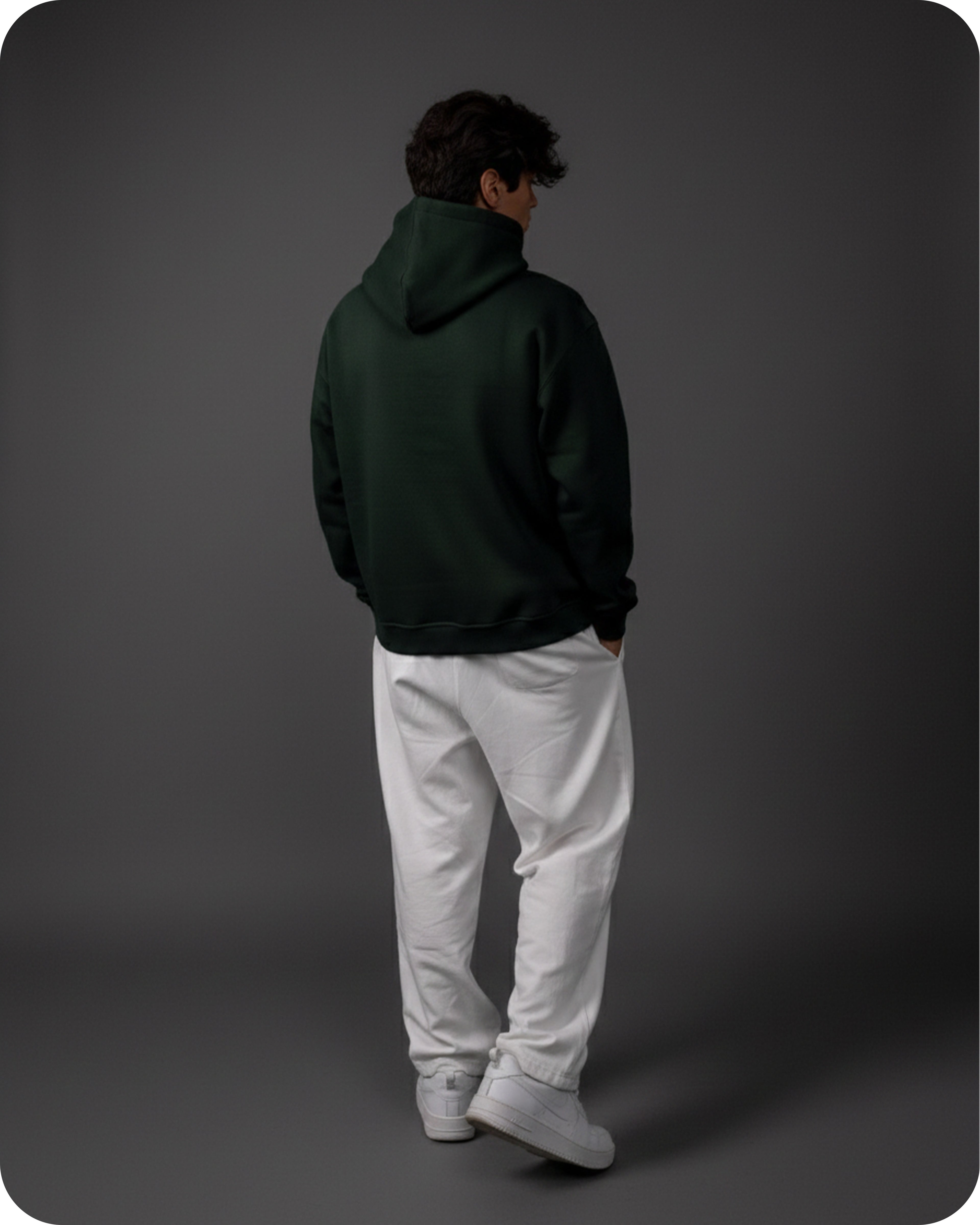Person wearing a dark green hoodie and white pants on a gray background