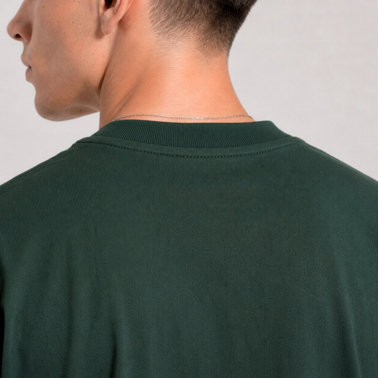Person wearing a dark green t-shirt against a plain background
