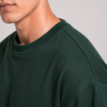 Person wearing a dark green shirt with a plain background