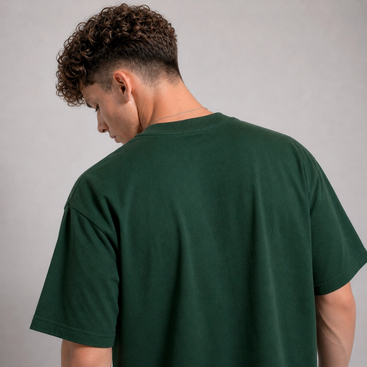 Person wearing a green t-shirt against a gray background