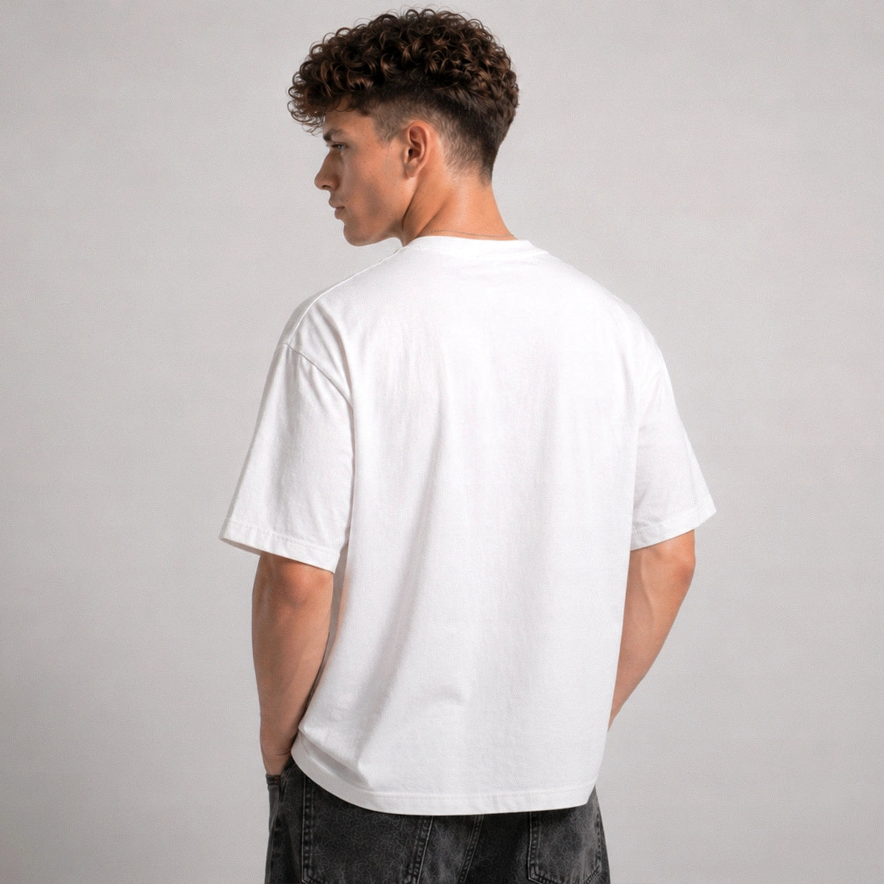 Person wearing a plain white t-shirt on a gray background