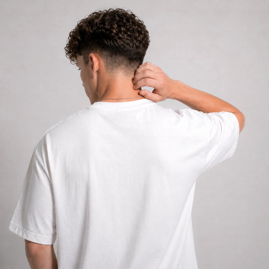 Person wearing a plain white t-shirt against a gray background