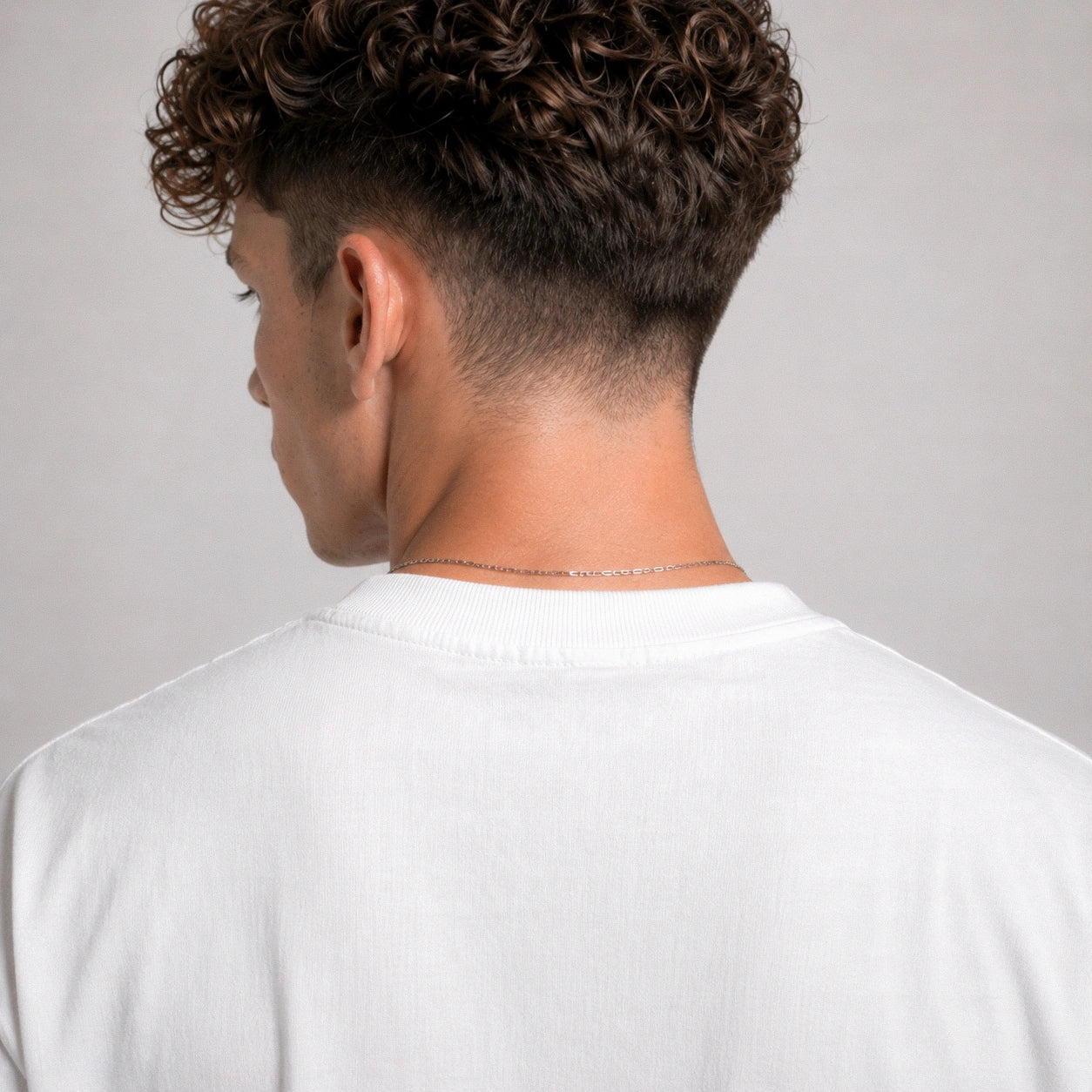 Person wearing a white shirt with a plain background