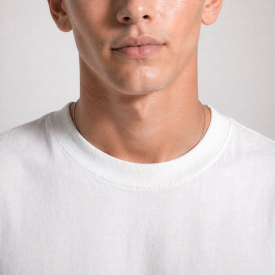 Close-up of a person wearing a plain white t-shirt against a neutral background